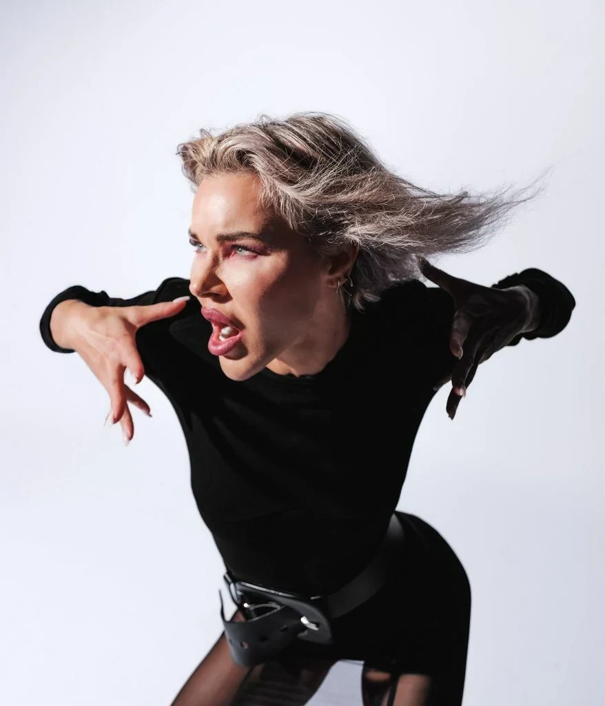 An exaggerated pointing gesture pose: Pointing straight at the lens with an exaggerated expression and hair still mid-whip captures an energy that a calm, composed face never will.