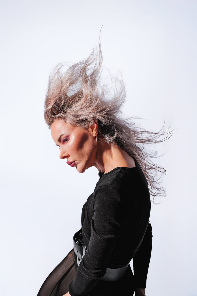 Calm expression, hair left loose and free against a plain background